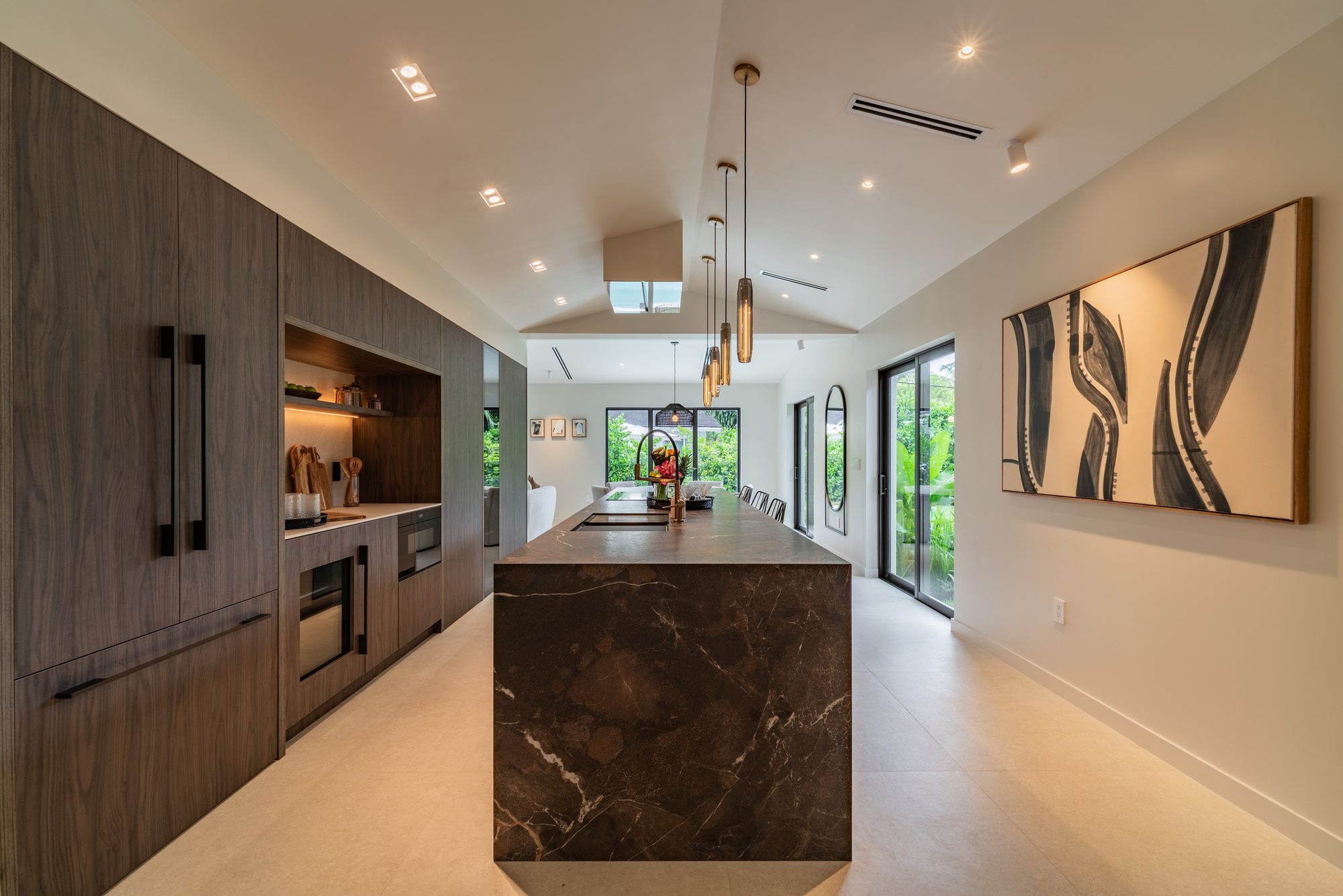 The kitchen with walnut-toned cabinetry and a deep, veined waterfall island